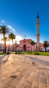 a mosque with a clock tower and pigeons in a courtyard at Explora BA, depto céntrico junto al Obelisco con espacio de trabajo in Buenos Aires