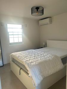 a bedroom with a white bed with a window at Bosparel met ruime tuin en airco! in Oisterwijk