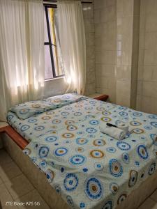 a bed with a blue and white comforter and a window at Hospedaje el balcon suite in Villavicencio