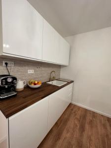 a kitchen with white cabinets and a bowl of fruit on the counter at The Hill Studio - Free Parking & Walk to Old Town in Vinohrady