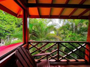 a balcony with two chairs and a view of palm trees at Casa Iguana in Puerto Viejo