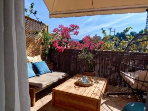 a patio with a table and a couch and flowers at Reginas studios & apartments - Bougainvillea Suite in Fiskardho