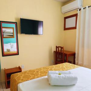 a hotel room with a bed and a tv on the wall at Hotel Akroama in Corumbaíba