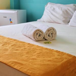 a stack of towels sitting on a bed at Hotel Akroama in Corumbaíba