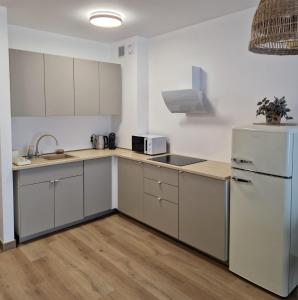 a kitchen with white cabinets and a white refrigerator at Apartament Sunset Resort Grzybowo in Grzybowo +17 photos