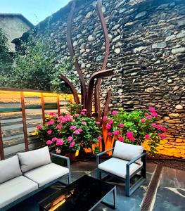 un patio con due sedie e fiori e un muro di pietra di Hotel Boutique La Neu a Benasque Altre 42 foto