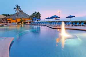 Una gran piscina con sillas y sombrillas azules. en Holiday Inn Veracruz-Boca Del Rio by IHG, en Veracruz