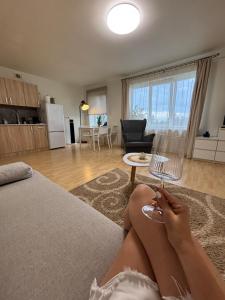 a woman sitting on a bed holding a wine glass at Self Check- in Cozy Apartment in Cēsis