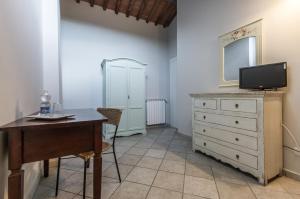 a room with a desk and a dresser with a television at I Terzi Di Siena - Rooms Only in Siena