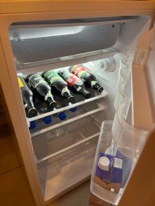 an open refrigerator filled with bottles of wine at Refúgio raiz pousada mineira in Camanducaia
