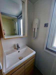 a bathroom with a sink and a mirror at Mobil-home domaine la yole 5 étoiles in Vendres