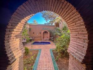 a brick archway leading to a backyard with a swimming pool at Le Sauvage Noble in Tissergat