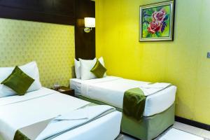 two beds in a hotel room with yellow walls at Mina Concorde Hotel in Makkah +37 photos