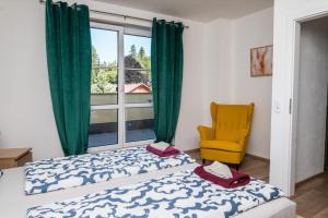 a bedroom with a bed and a window and a yellow chair at Apartmá Kateřina Velké Losiny in Velké Losiny