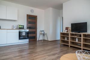 a kitchen with white cabinets and a flat screen tv at Apartmá Kateřina Velké Losiny in Velké Losiny