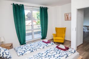 a bedroom with a bed and a yellow chair and a window at Apartmá Kateřina Velké Losiny in Velké Losiny