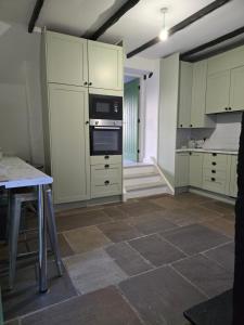 a kitchen with white cabinets and a table in it at Swallow Cottage Middleham in Middleham