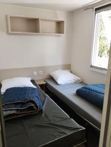 two beds in a small room with a window at Mobil home 6 personnes in La Celle-sous-Gouzon