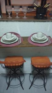 ein Tisch mit zwei Hockern mit Tellern und Tassen darauf in der Unterkunft Ecovalle São Thomé - Cabana Mallki Wasi in São Thomé das Letras