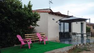 a patio with pink chairs and a table and an umbrella at Maison au calme L'échappée Tarnaise in Cunac