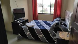 a bedroom with a bed and a flat screen tv at ApartHotel CadenaTours in Tupiza