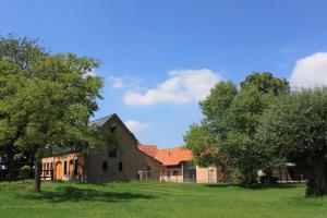 an old brick building with trees in a field at De Maalderie Holiday Home in Houthulst