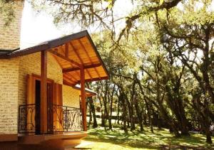 a building with a balcony with trees in the background at Chalés Montanha Serrana - Monte Verde in Monte Verde
