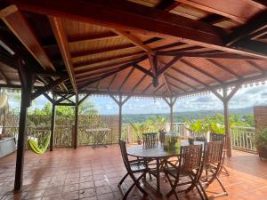 eine Terrasse mit einem Tisch und Stühlen mit Aussicht in der Unterkunft Cottage Palmier Rouge in La Trinité