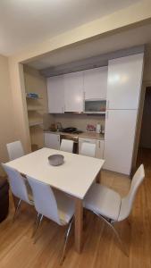 a kitchen with a white table and white chairs at Apartman Dona in Jagodina +5 photos