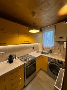 a kitchen with yellow cabinets and a stove top oven at Gold Vibe Apartment in Topliţa