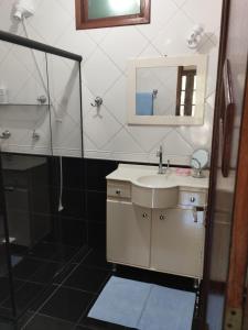 Un baño con lavabo, ducha y espejo. en Apartamento aconchegante!, en Cachoeiro de Itapemirim