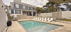 ein Haus mit einem Swimmingpool mit Liegestühlen in der Unterkunft Hotel Alpre in Villa Carlos Paz