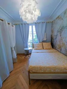 Un dormitorio con dos camas y una lámpara de araña. en Au Petit Trianon Bleu, en Versalles