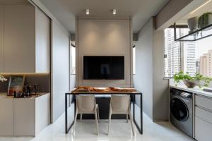 a kitchen with a table with chairs and a tv at Loft Quero-Quero in Águas Claras