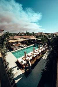 a pool with chaise lounges and chairs next to a resort at Wakana Alaçatı in Alacati