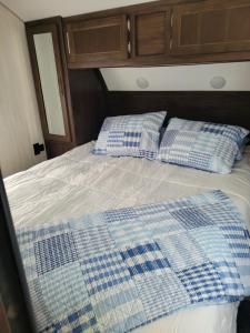 a bed with two blue and white pillows on it at Cozy Camping in Hot Springs