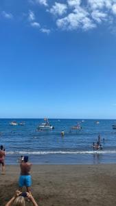 a group of people on the beach with boats in the water at Casa Arena y Mar in Telde