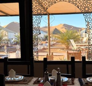 a table with a view of a desert through a window at lion Desert luxury Camp in Merzouga