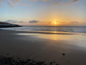 a sunset on a beach with the ocean at Casa Arena y Mar in Telde