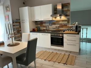 a kitchen with white cabinets and a table and a stove at La Casina sul Tetto in Albano Laziale