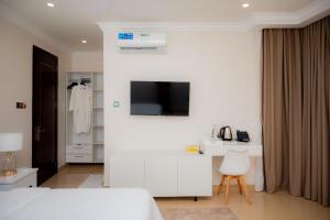 a white room with a bed and a television on a wall at Premier Hotel Zanzibar Airport in Zanzibar City