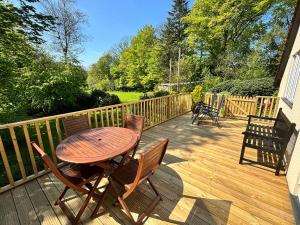 una mesa de madera y sillas en una terraza de madera en Little Oaklands, en Lostwithiel