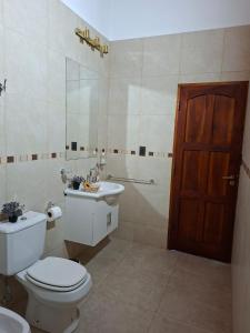 a bathroom with a toilet and a sink and a door at Las Casuarinas in San José