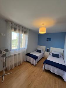 two beds in a room with blue walls and a window at El Mirador de Segovia in Basardilla