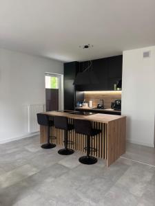 a kitchen with black cabinets and a counter with stools at Apartamenty Cegielnia 1 Lux-Haus in Gorzów Wielkopolski