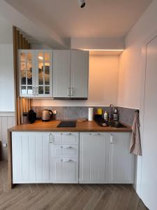a kitchen with white cabinets and a wooden counter top at Apartamenty Oakland in Debina