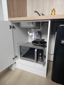 a microwave in a kitchen under a sink at Joli studio plein centre proche Gare Orléans in Orléans
