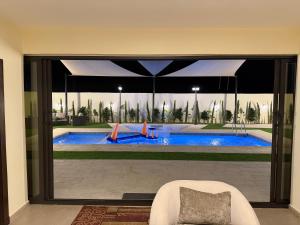a view of a swimming pool through a large glass window at Giving Vibes Chalet in Amman