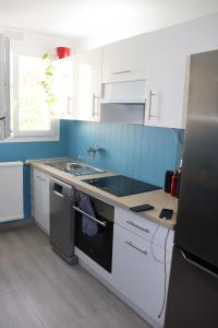 a kitchen with white cabinets and a sink at Les Erables Appart - 3 chambres - Spacieux et moderne avec balcon, parking et wifi in Saint-Jean-de-la-Ruelle +7 photos