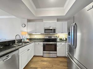a kitchen with white cabinets and a stainless steel refrigerator at Sunset Crossing in Gulf Shores +34 photos